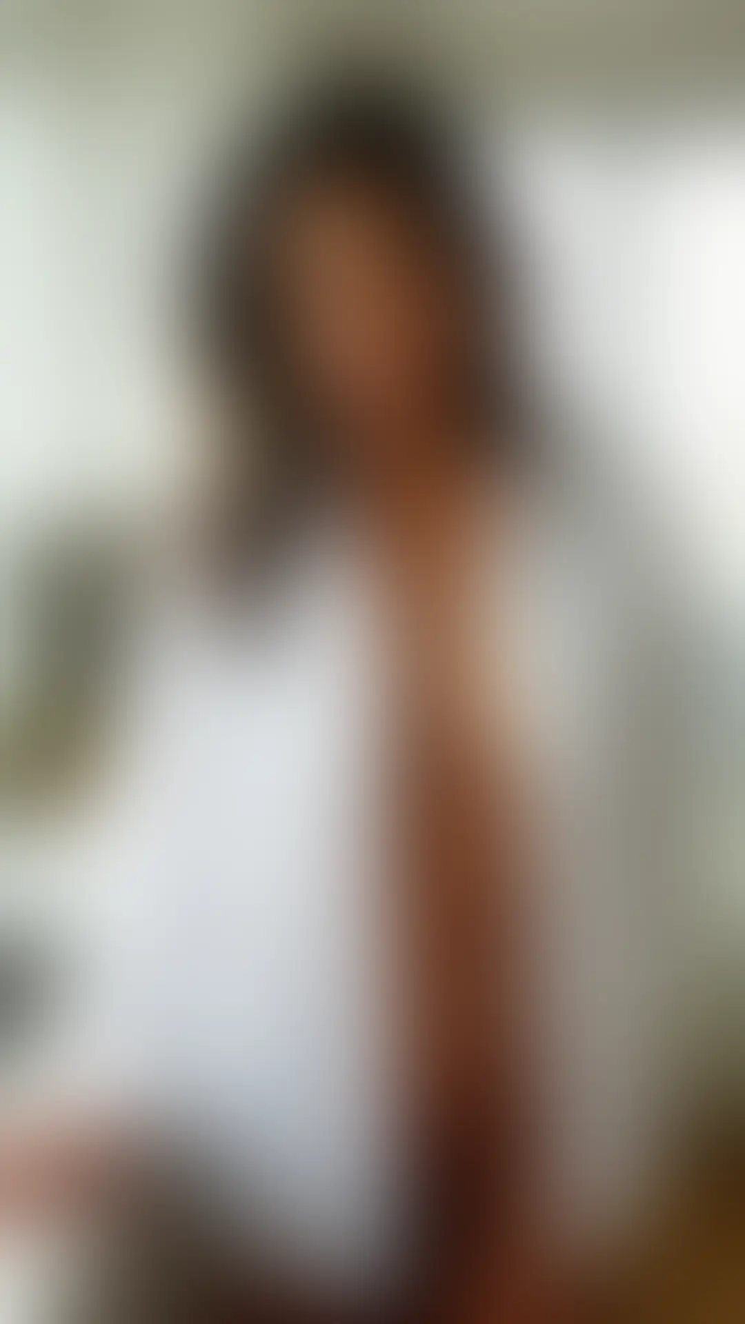Beautiful woman in an open white dress shirt standing in a bright kitchen